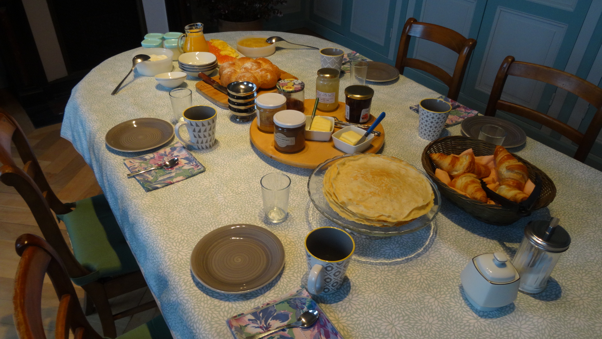 Breakfast table with bread, pastries, yogurts, pancakes, orange juice and fresh fruit